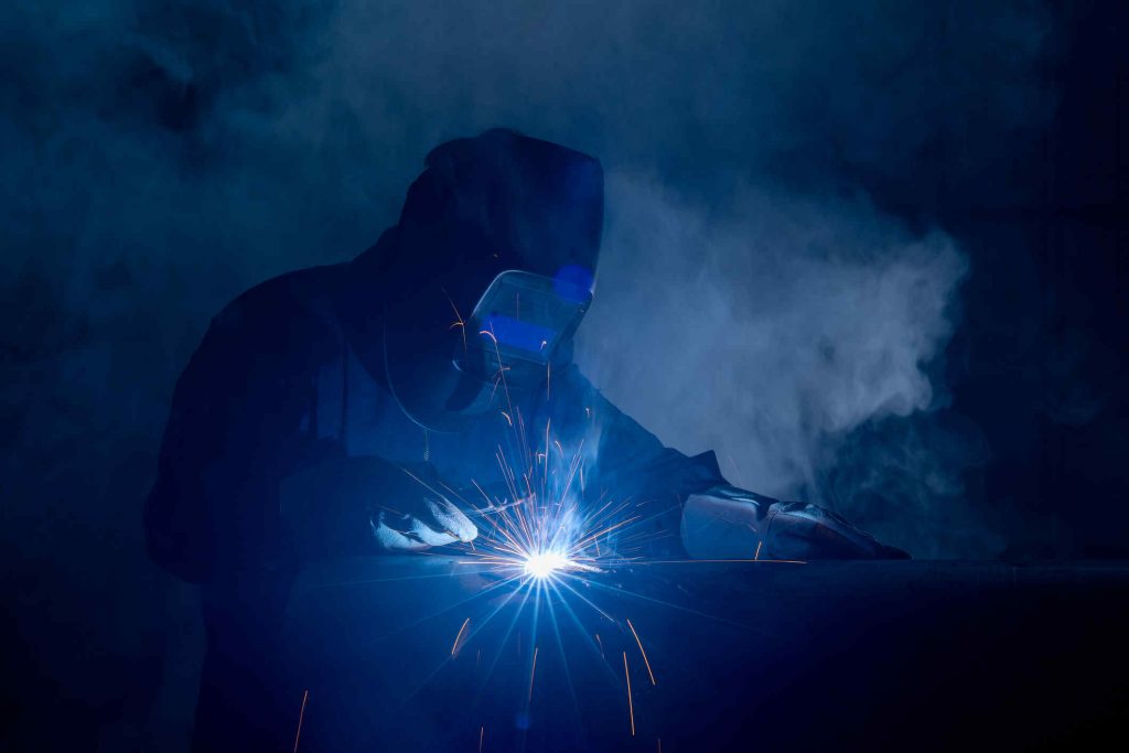 Professional welder and mask welding metal pipe at welding school.